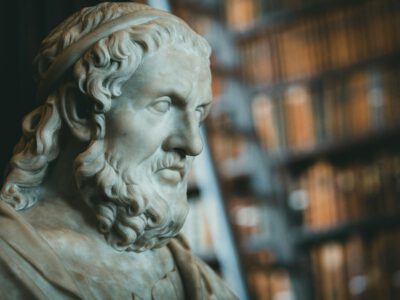 Close-up of a classical marble statue with blurred bookcases in the background.